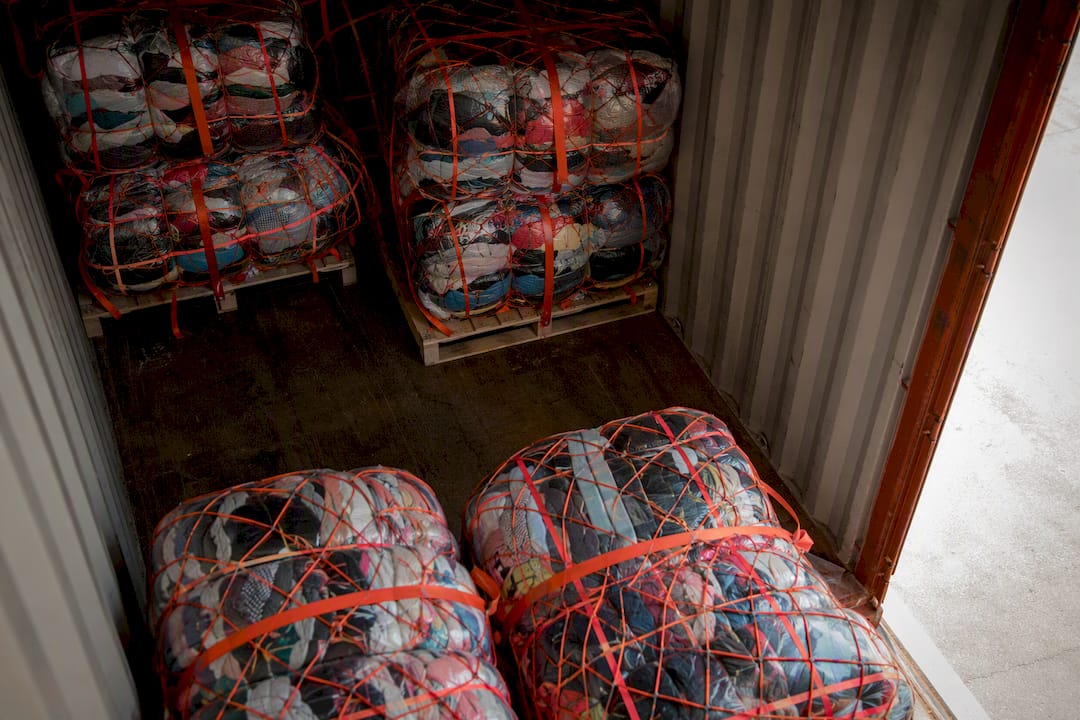 Stacked pallets of compressed clothing bales in container