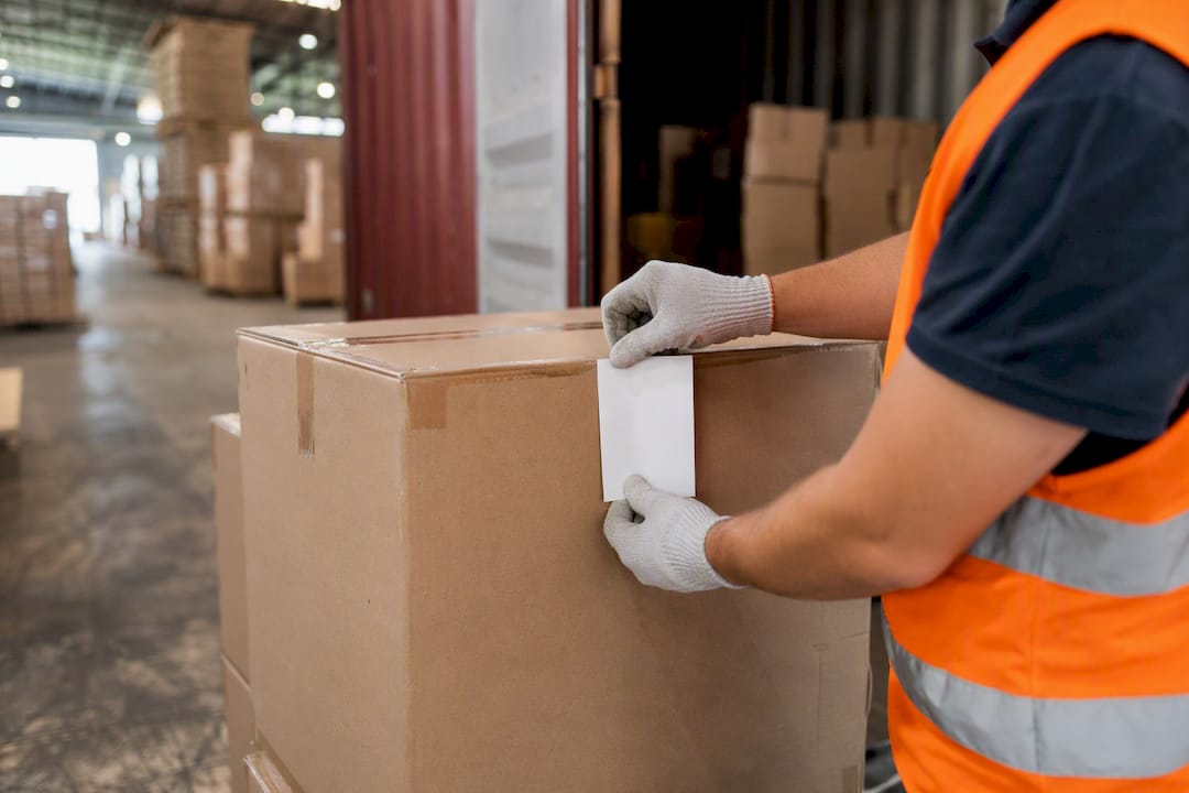Worker labeling carton in warehouse