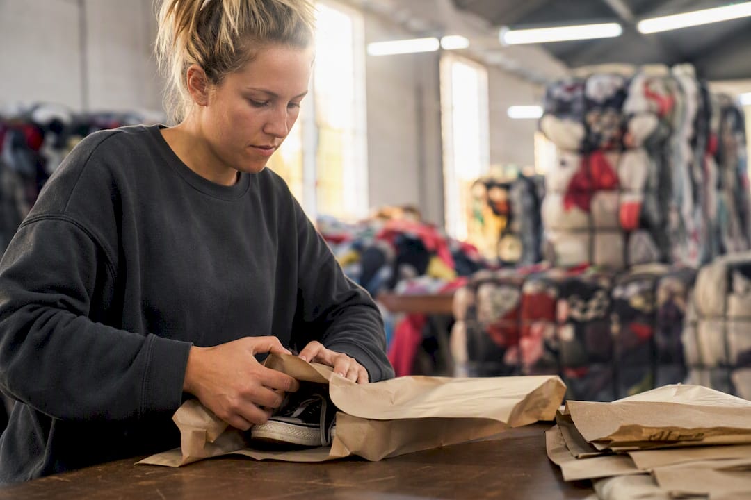 Hands wrapping used footwear in recycled materials