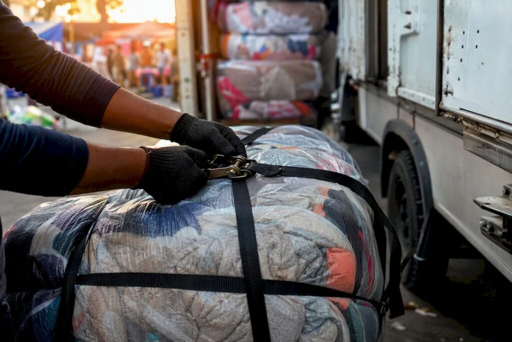Hands tightening bale strap near container