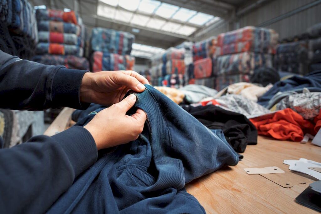 Hands inspecting used clothing stitching