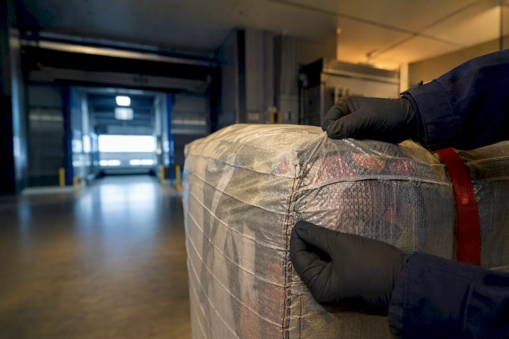 Customs inspector examining anonymous textile bale