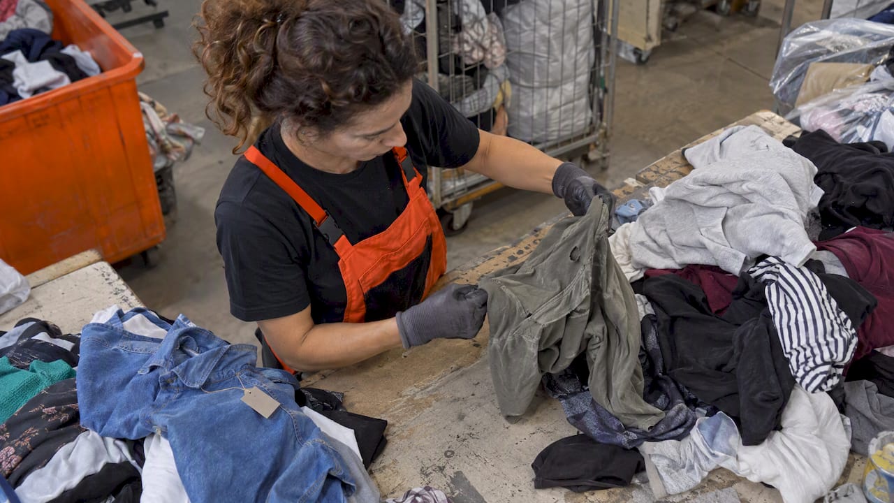 Inspector sorts sampled garments for reuse or recycling